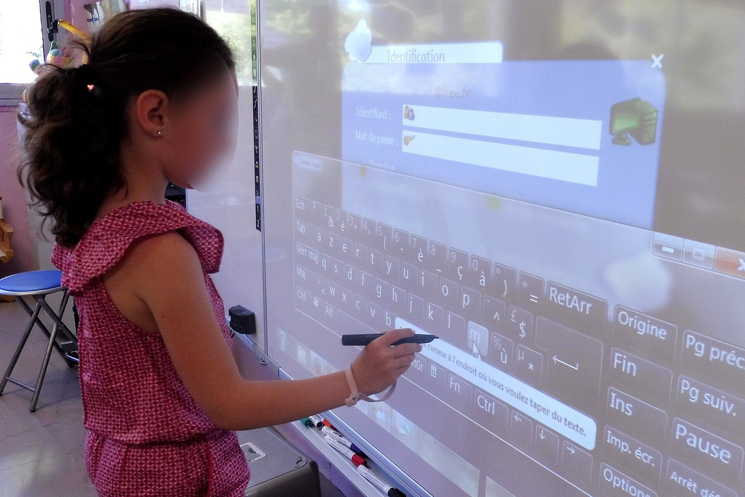 A student at an interactive classroom panel, face blurred for privacy